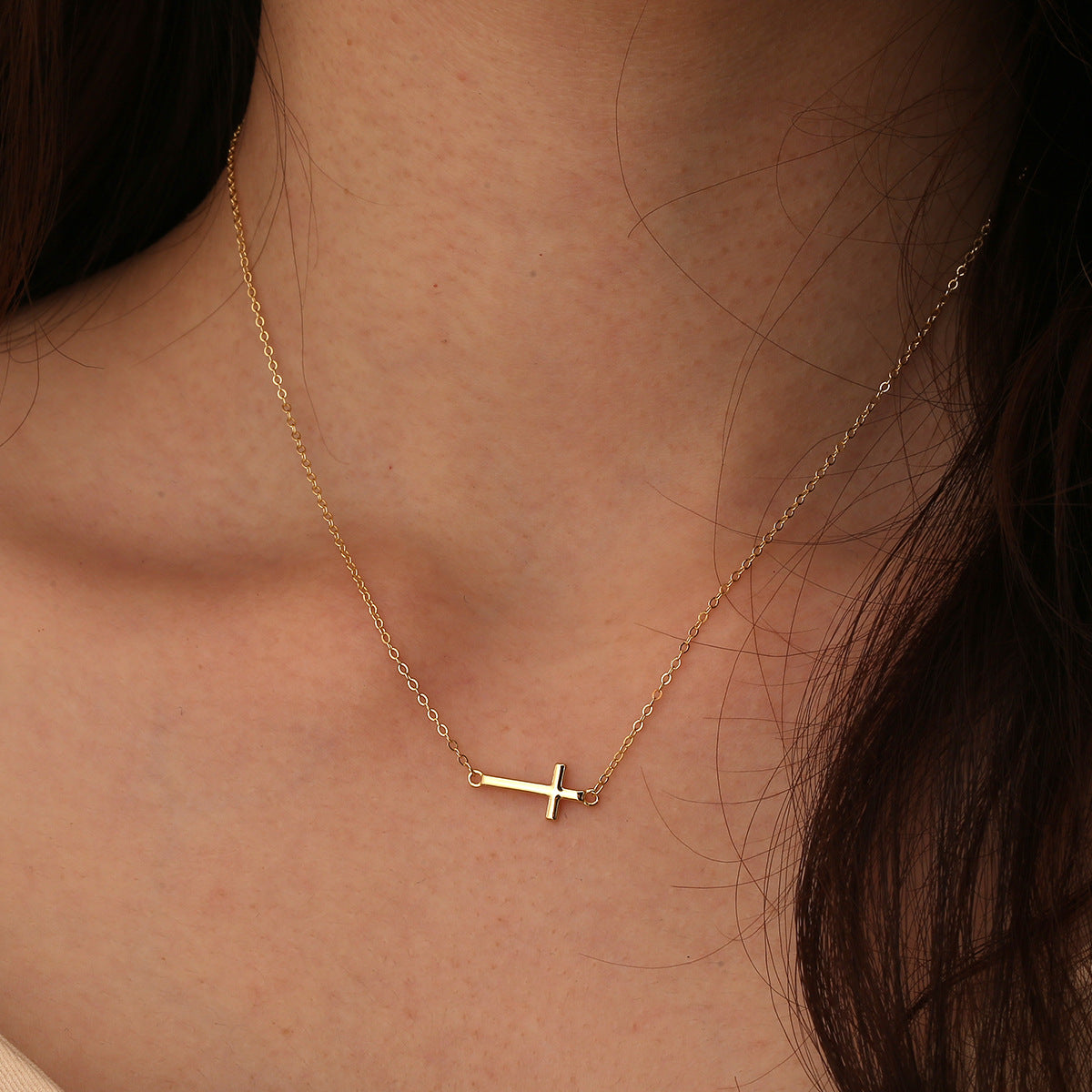 minimalist sideways cross necklace worn at the collarbone
