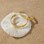 Gold-tone open cuffs resting on a pale shell