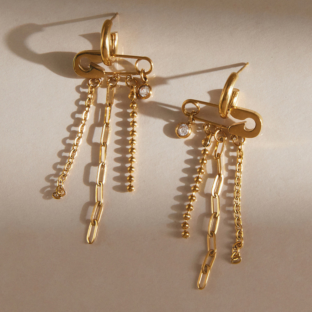 Pair of safety pin motif earrings laid flat