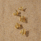 Gold-tone ring styling arrangement on sand
