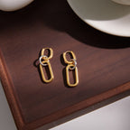 pair of two-tone linked drop earrings on a wooden surface