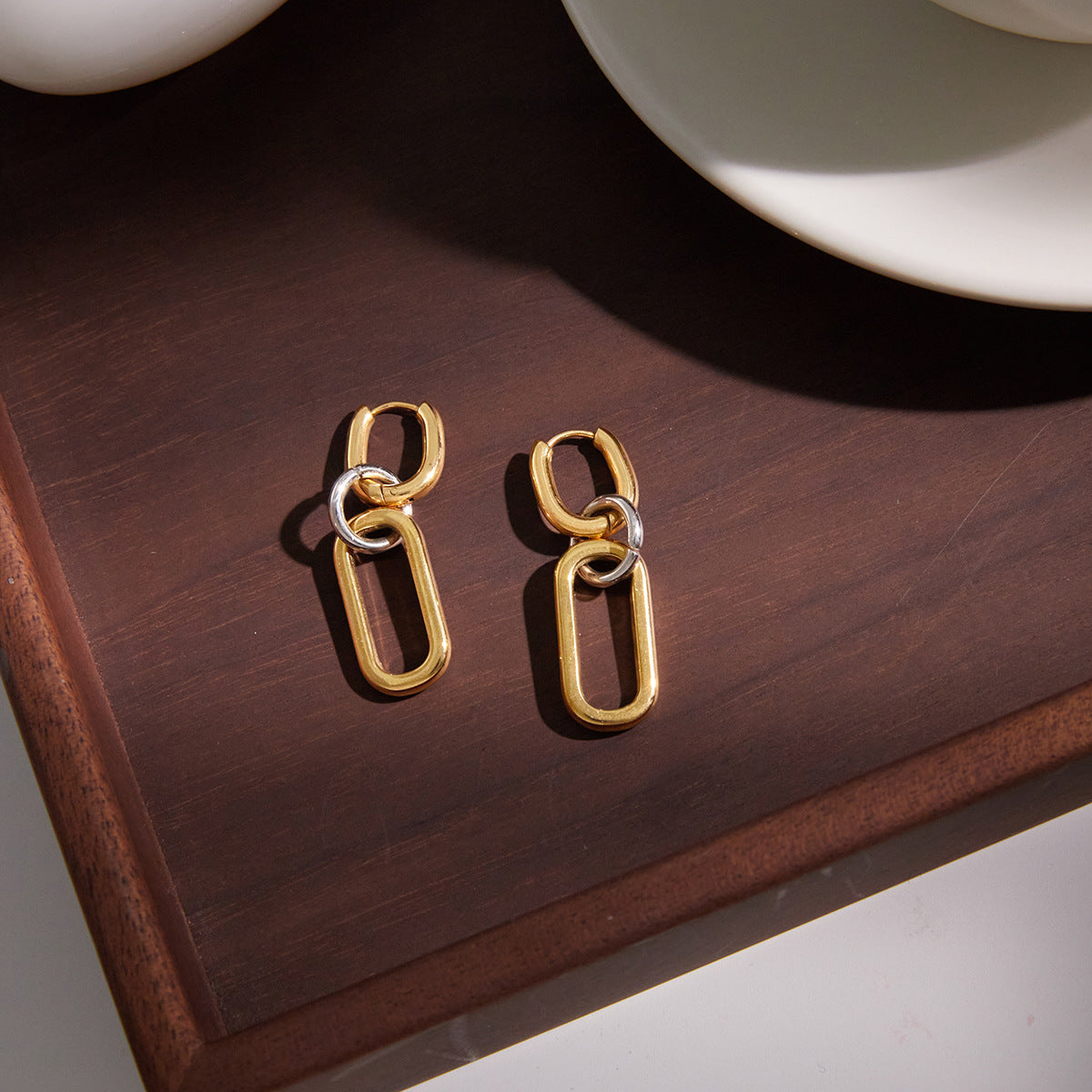 pair of two-tone linked drop earrings on a wooden surface
