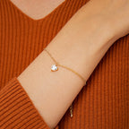 model wearing a fine chain bracelet with a faceted clear heart
