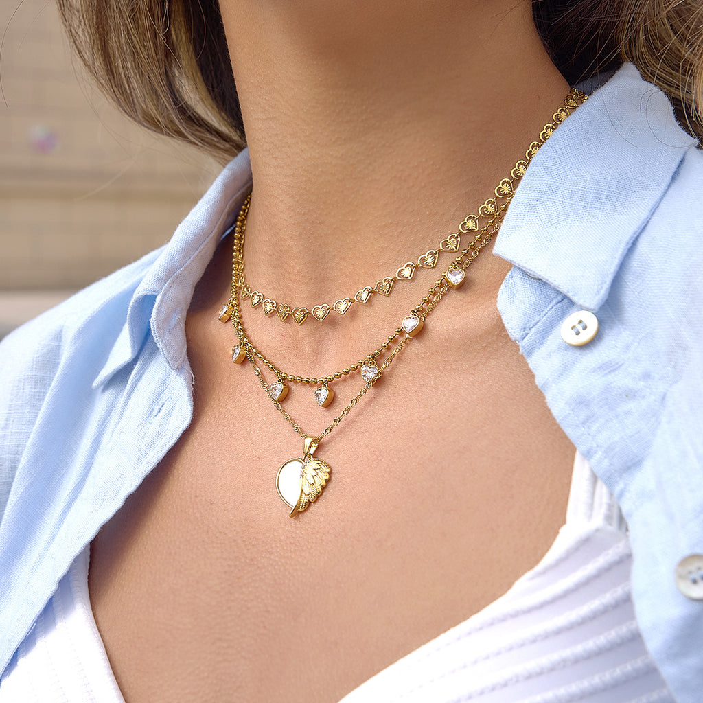 Winged heart necklace layered with separate heart-link designs