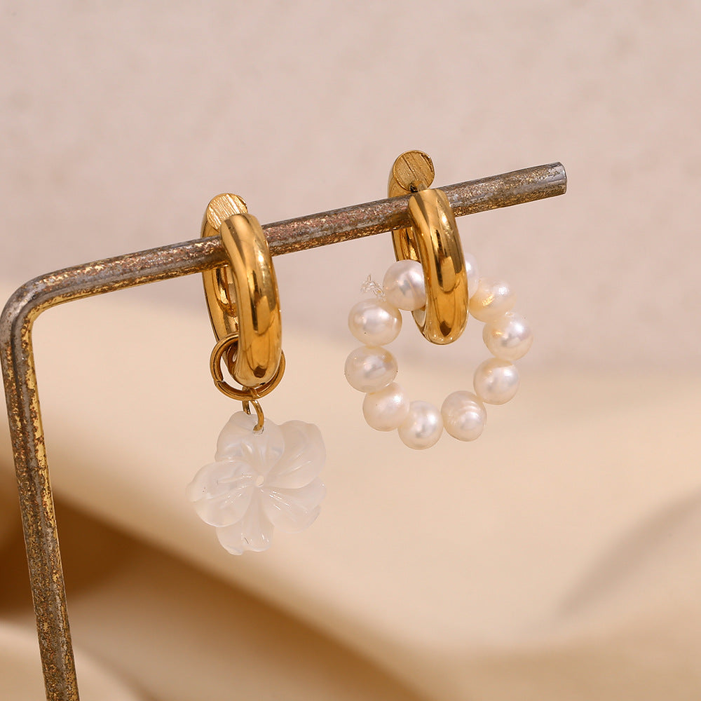 mismatched pearl and shell huggie earrings displayed on a metal stand