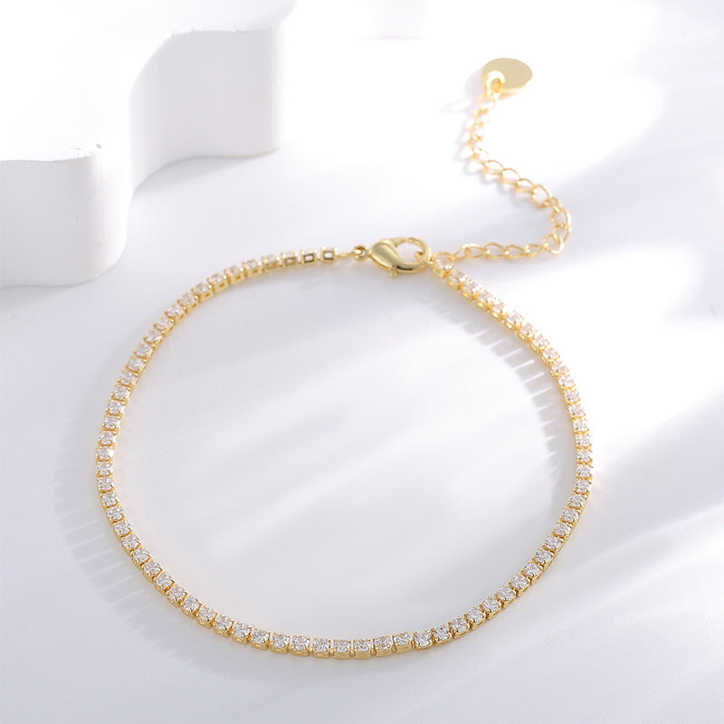 clear stone tennis anklet arranged beside a white display