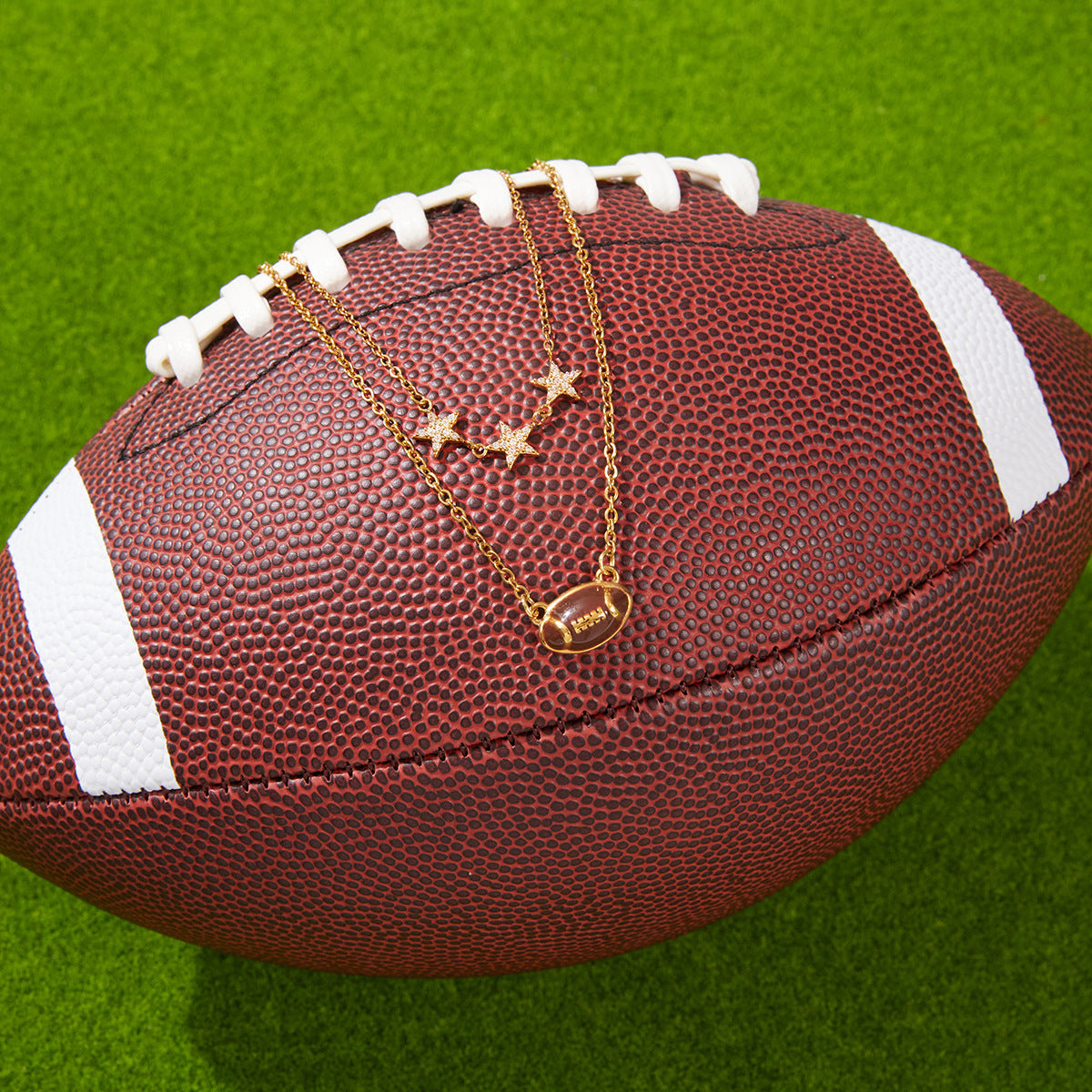 gold plated football necklace arranged on a sports ball