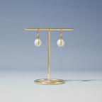 White ball drop hoop earrings on a stand