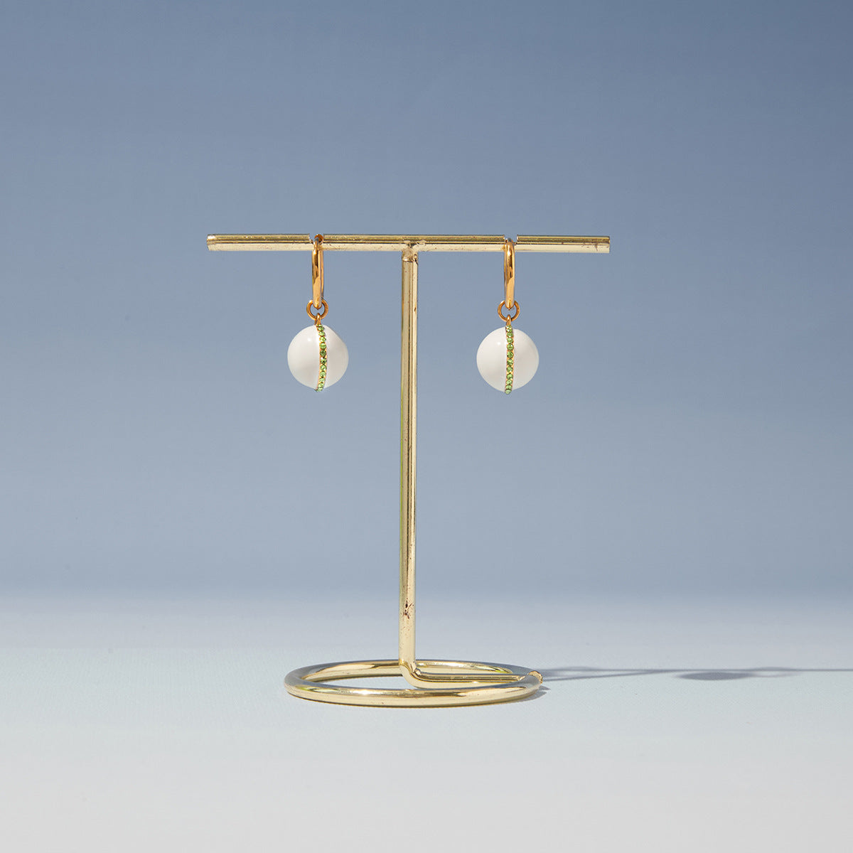 White ball drop hoop earrings on a stand