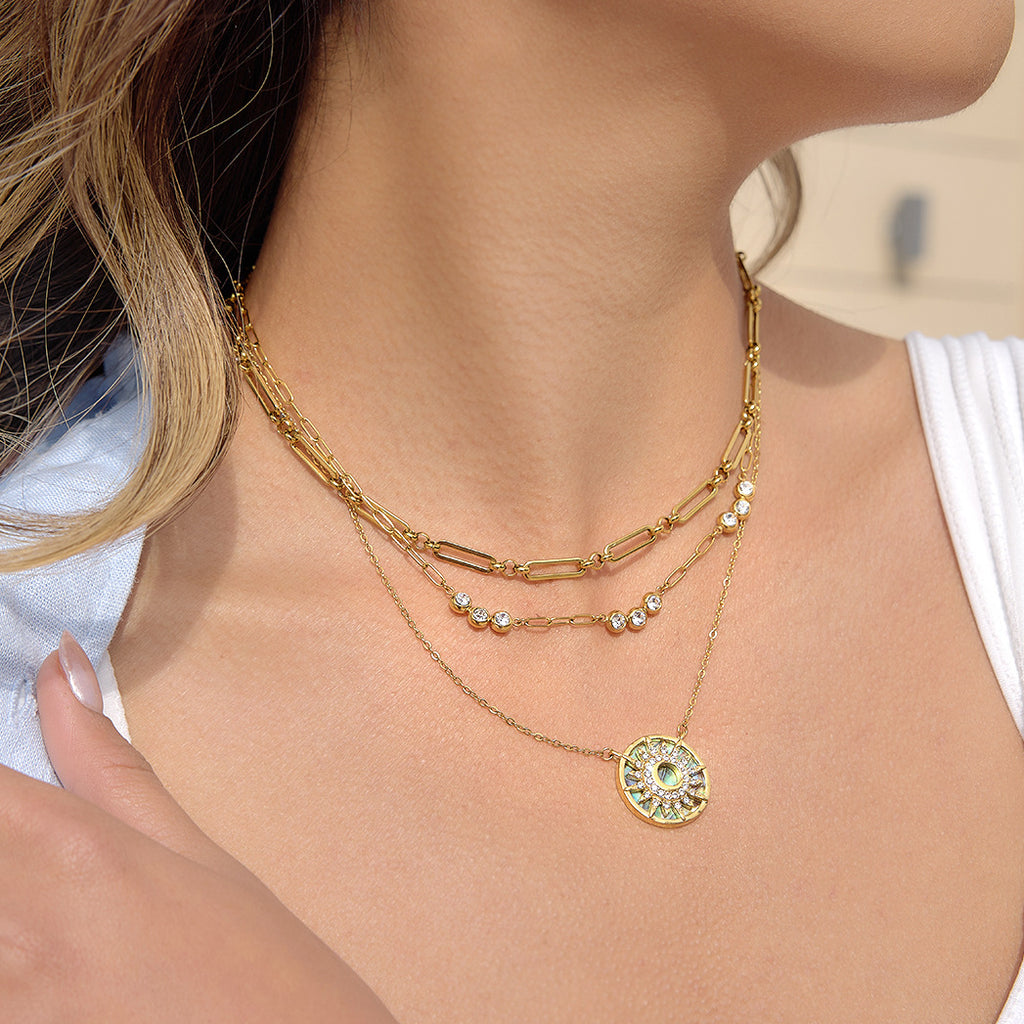 Patterned sun pendant worn with layering chains