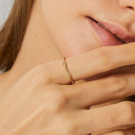 close worn view of slim gold plated three-stone stacking ring
