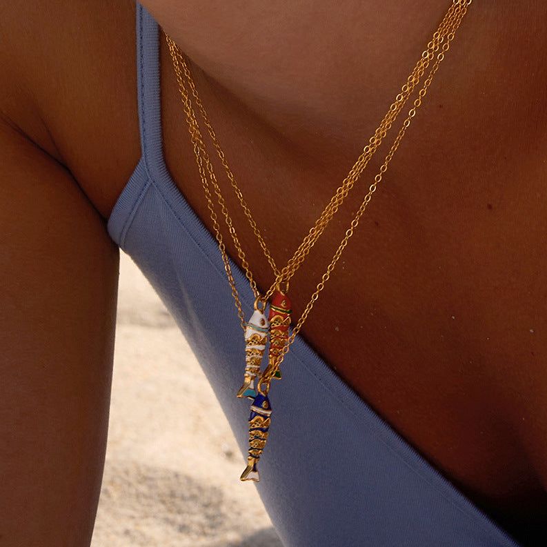 Three colored fish pendant necklaces worn together