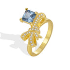 isolated gold plated bow ring with blue square center stone