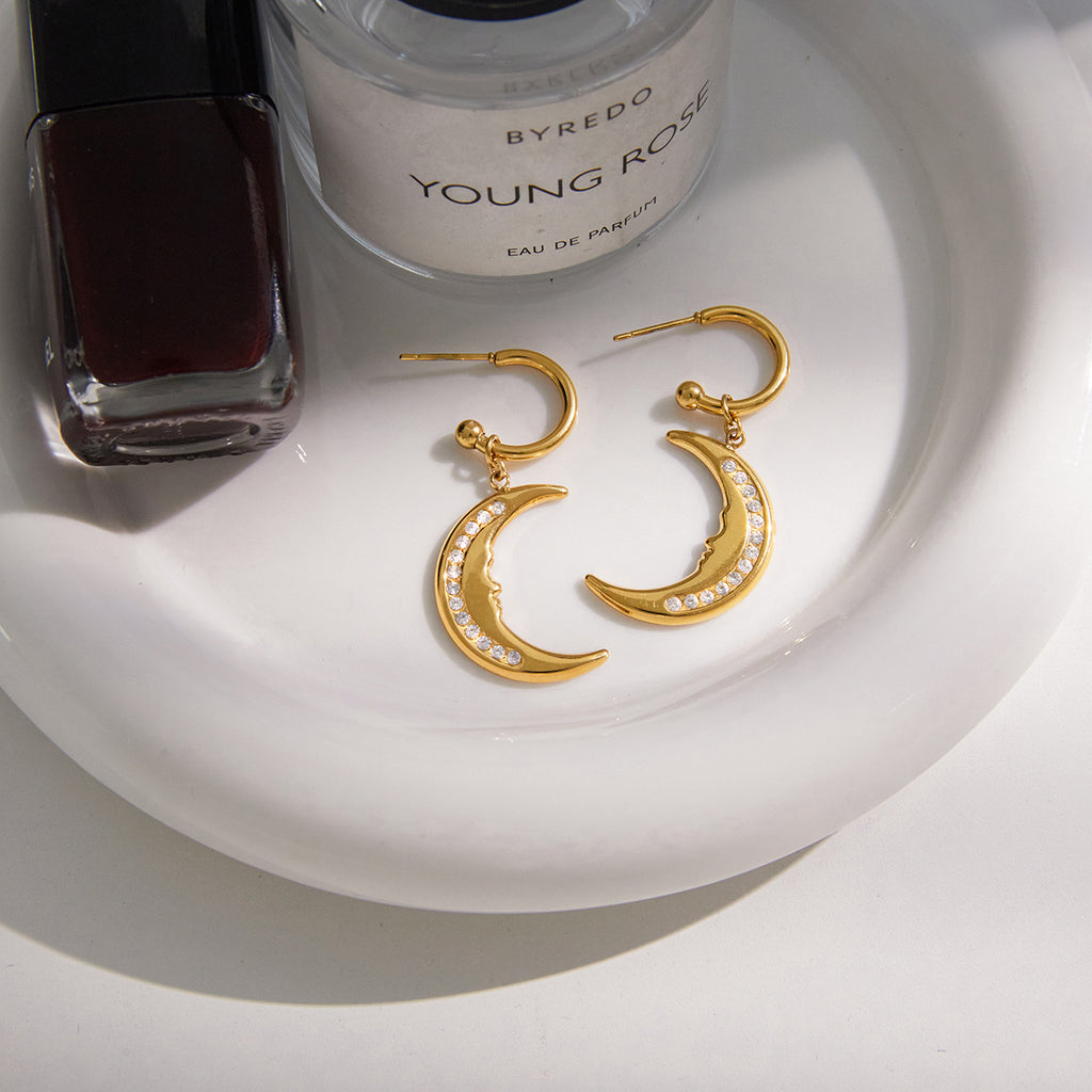 pair of gold plated crescent moon earrings on a white tray