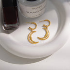pair of gold plated crescent moon earrings on a white tray
