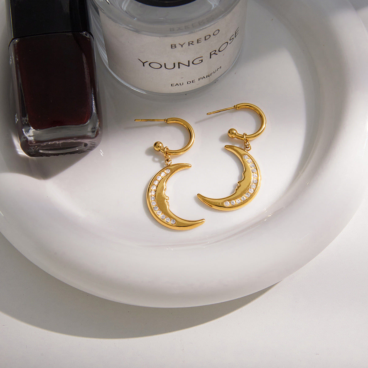 pair of gold plated crescent moon earrings on a white tray