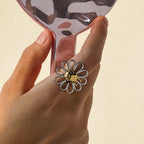 Two-tone open-petal flower ring worn on a hand