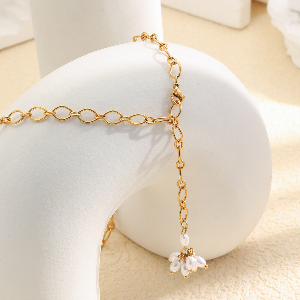 Gold plated open-link Y necklace with a white faux pearl flower on a display block