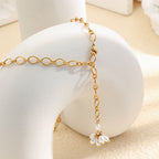 Gold plated open-link Y necklace with a white faux pearl flower on a display block