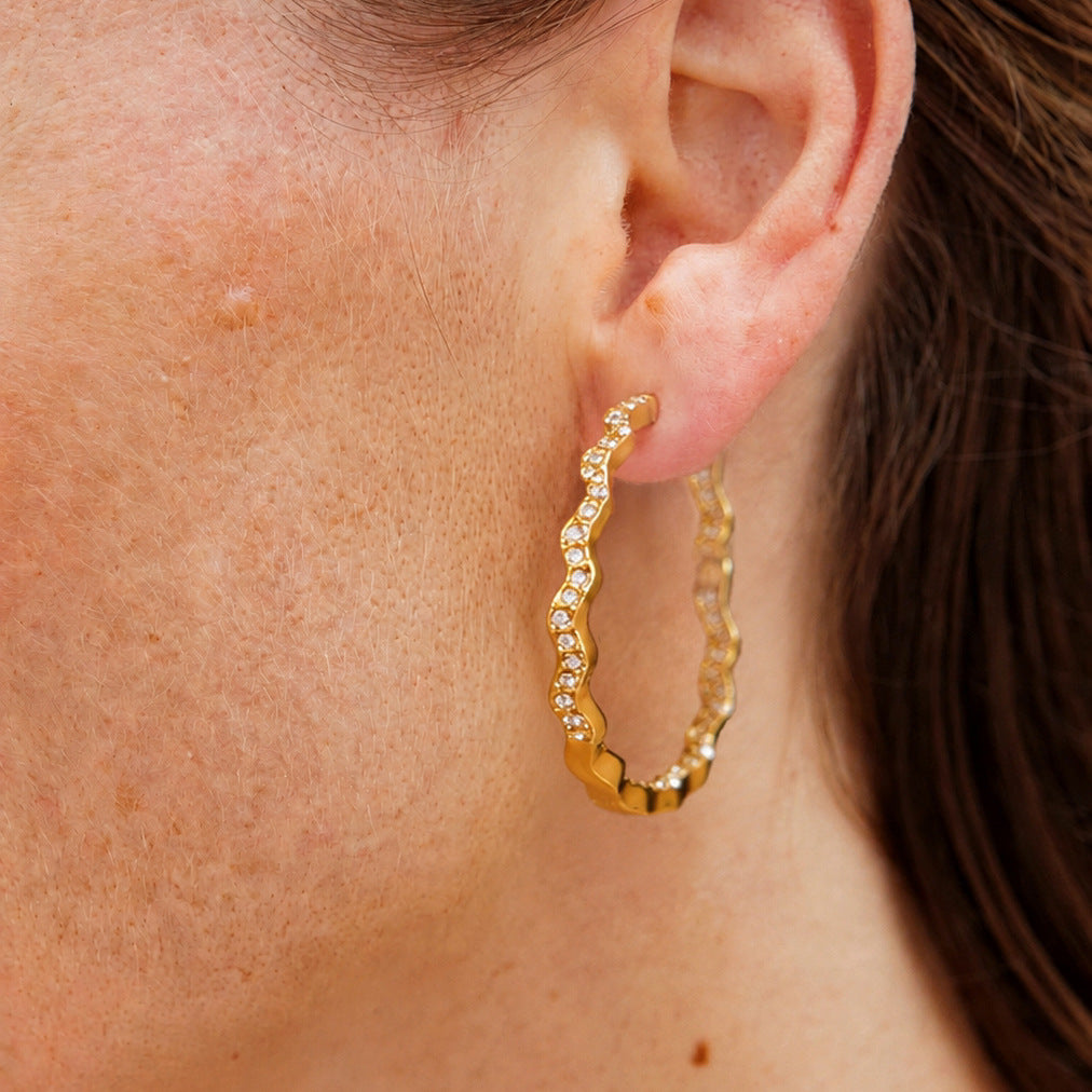Wavy rhinestone hoop worn on an ear