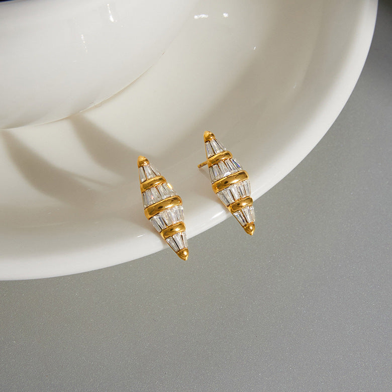 Tapered stone stud earrings displayed beside a cup