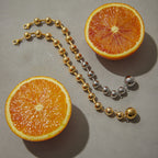 Gold and two-tone ball bracelets arranged beside orange slices