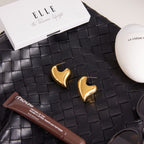 Asymmetric heart and elongated oval stud earrings styled flat lay