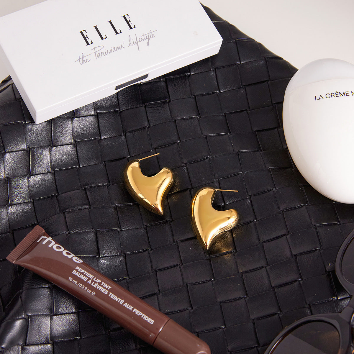 Asymmetric heart and elongated oval stud earrings styled flat lay