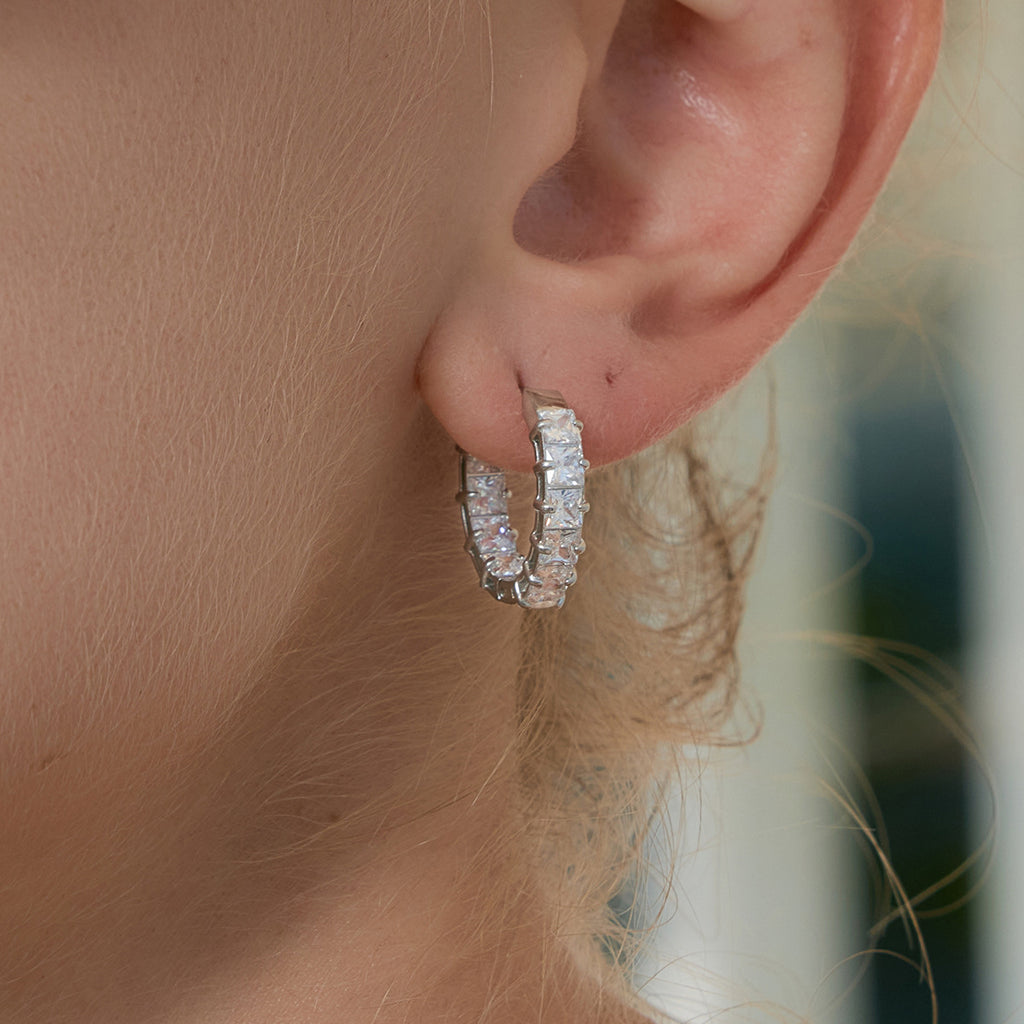 close view of the square clear stones on the silver huggies