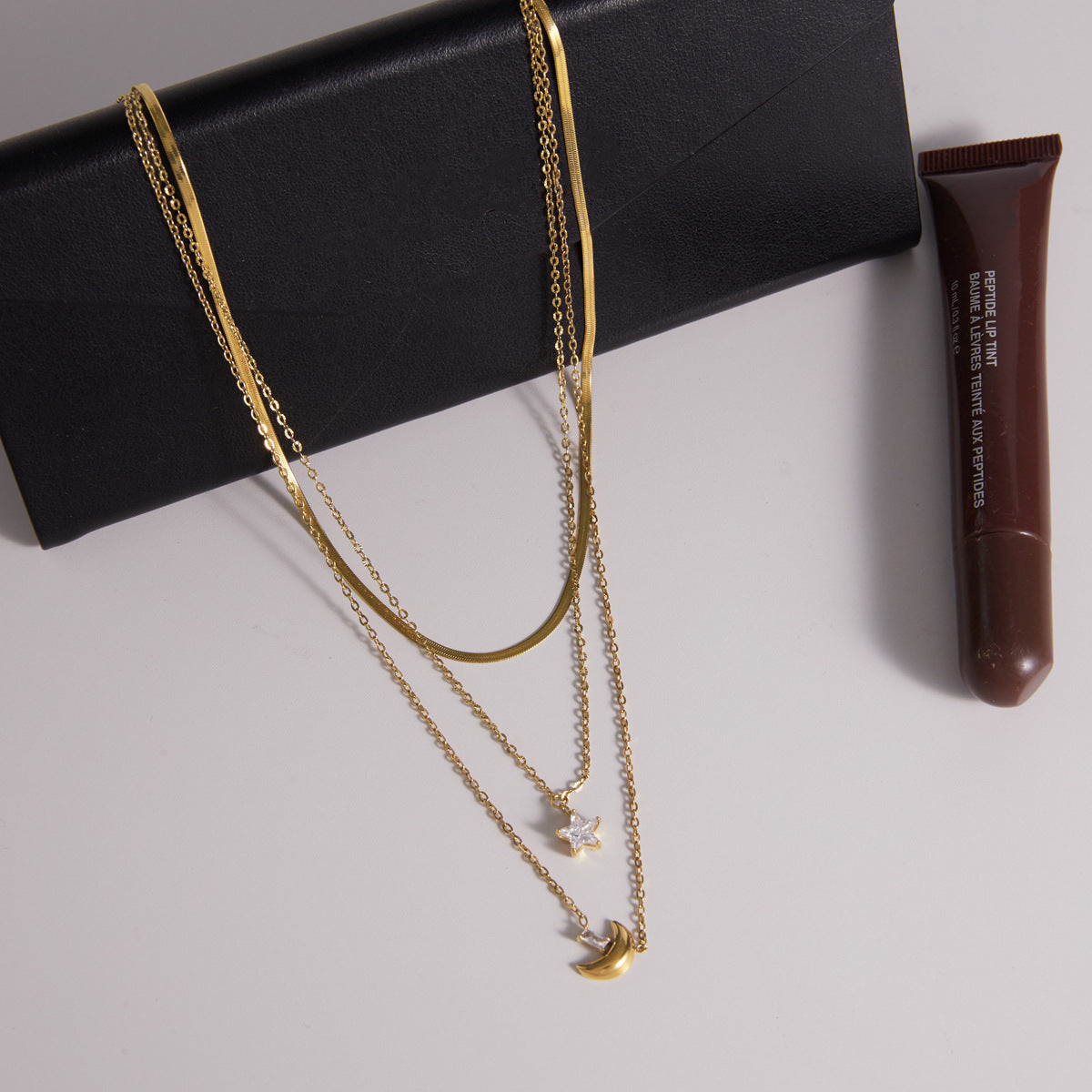 Triple chain necklace displayed on a black accessory