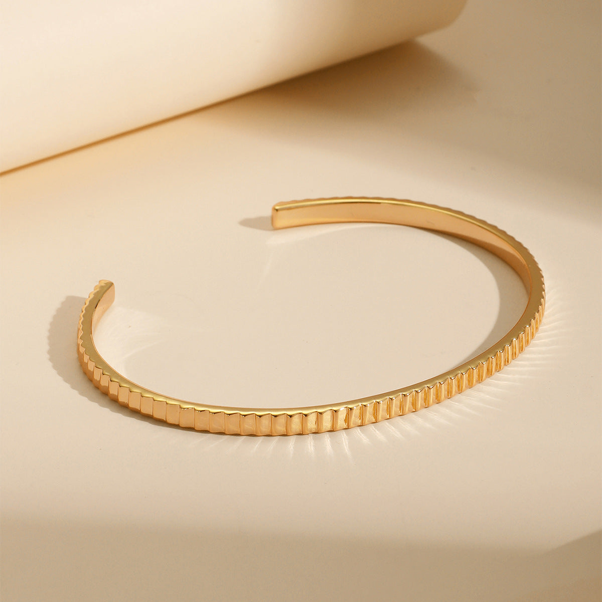slim ribbed brass cuff bracelet on a warm display