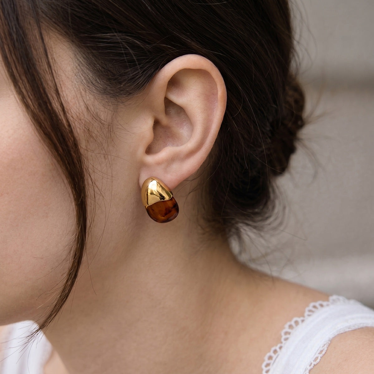 Brown resin teardrop stud worn on an ear