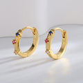 gold plated multicolor stone huggie earrings standing in studio