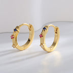 gold plated multicolor stone huggie earrings standing in studio