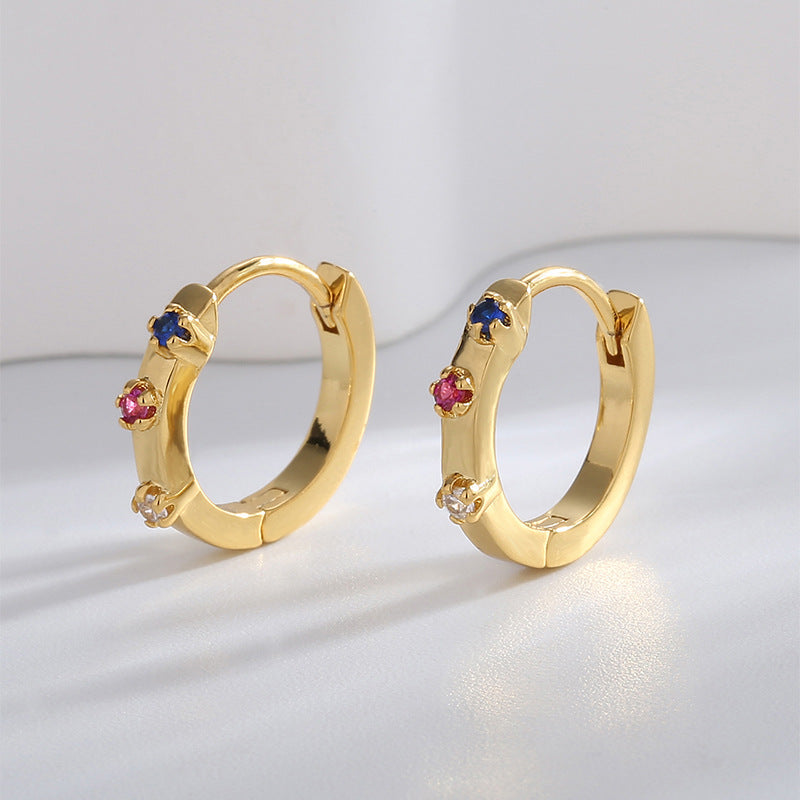 gold plated multicolor stone huggie earrings standing in studio