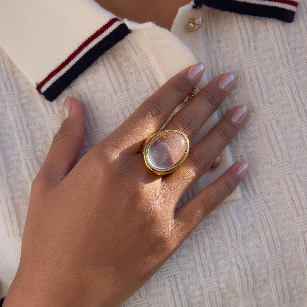 clear oval cabochon cocktail ring beside a coffee cup