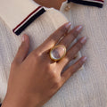 clear oval cabochon cocktail ring beside a coffee cup
