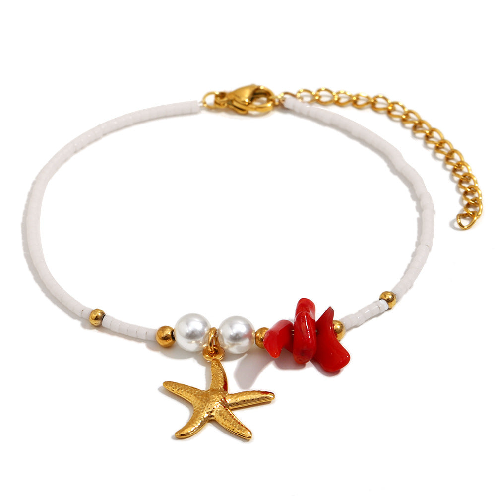 isolated gold plated stainless steel starfish bracelet with red and white beads