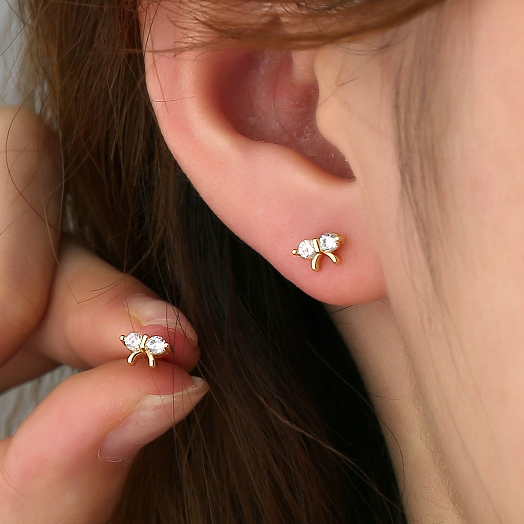 small clear stone bow stud earring worn on the lobe