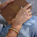 Gold plated pearl hand chain bracelet styled with a bangle