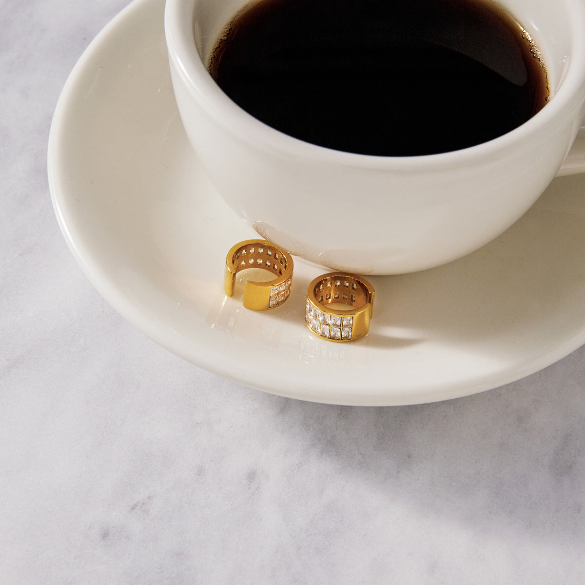 Stone-set cuffs beside a coffee cup