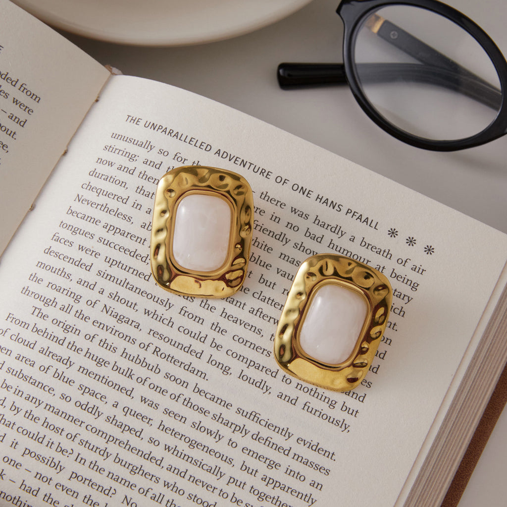 White resin rectangular earrings on an open book