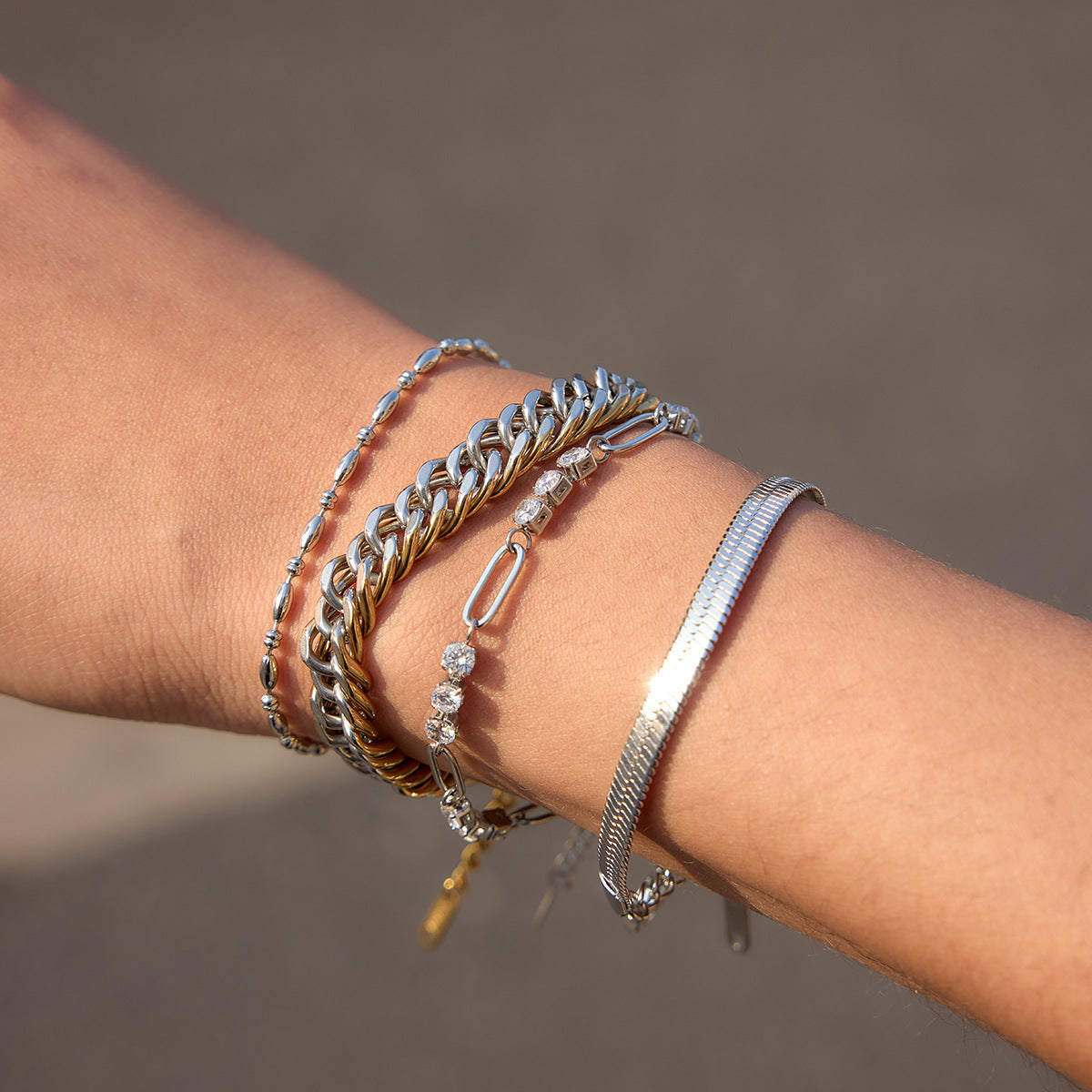 two-tone stainless steel Cuban bracelet worn with slim chains