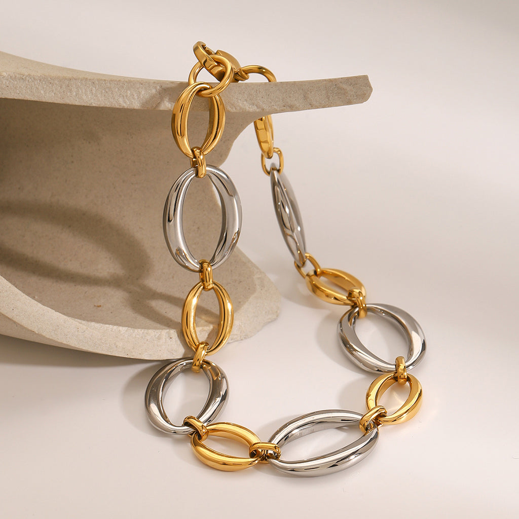 Gold and silver oval link bracelet hanging from a display