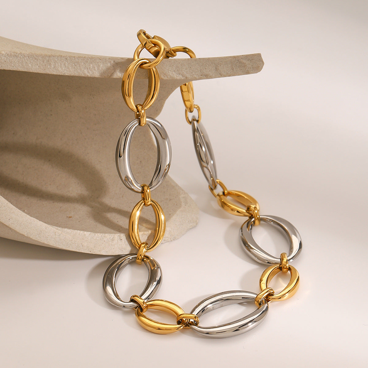 Gold and silver oval link bracelet hanging from a display