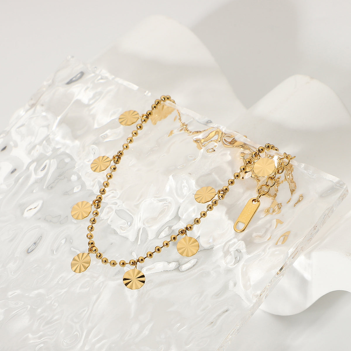 Beaded anklet with radial-pattern discs viewed diagonally