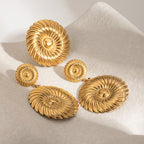 Two linked spiral earrings and reference ring arranged on stone