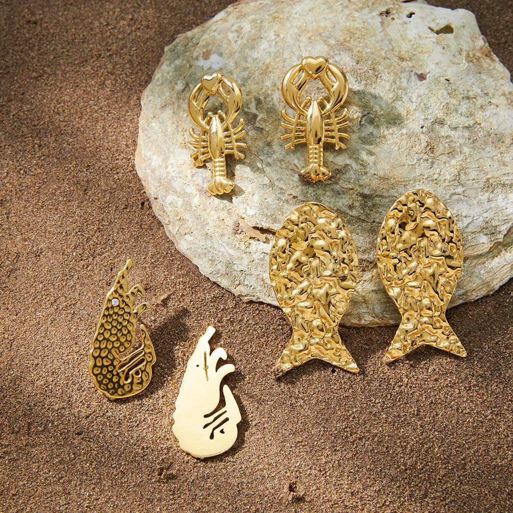 Three gold-tone sea creature earring styles on stone
