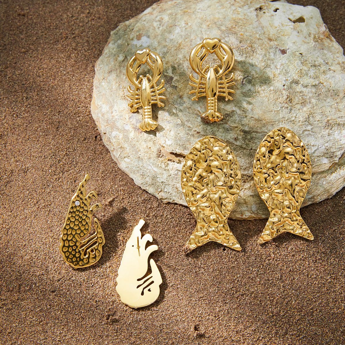 Three gold-tone sea creature earring styles on stone