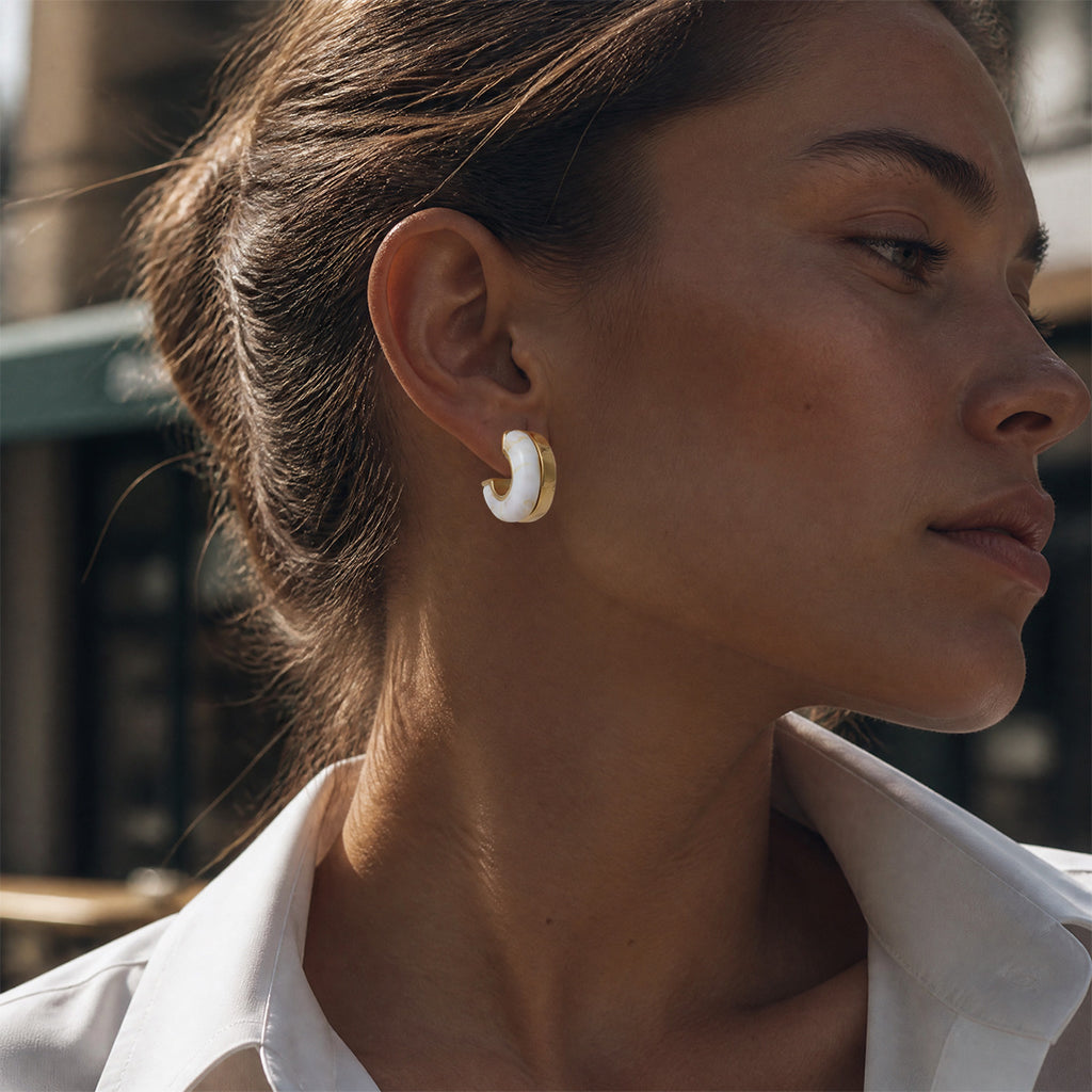 White and gold tone resin earring in a profile view